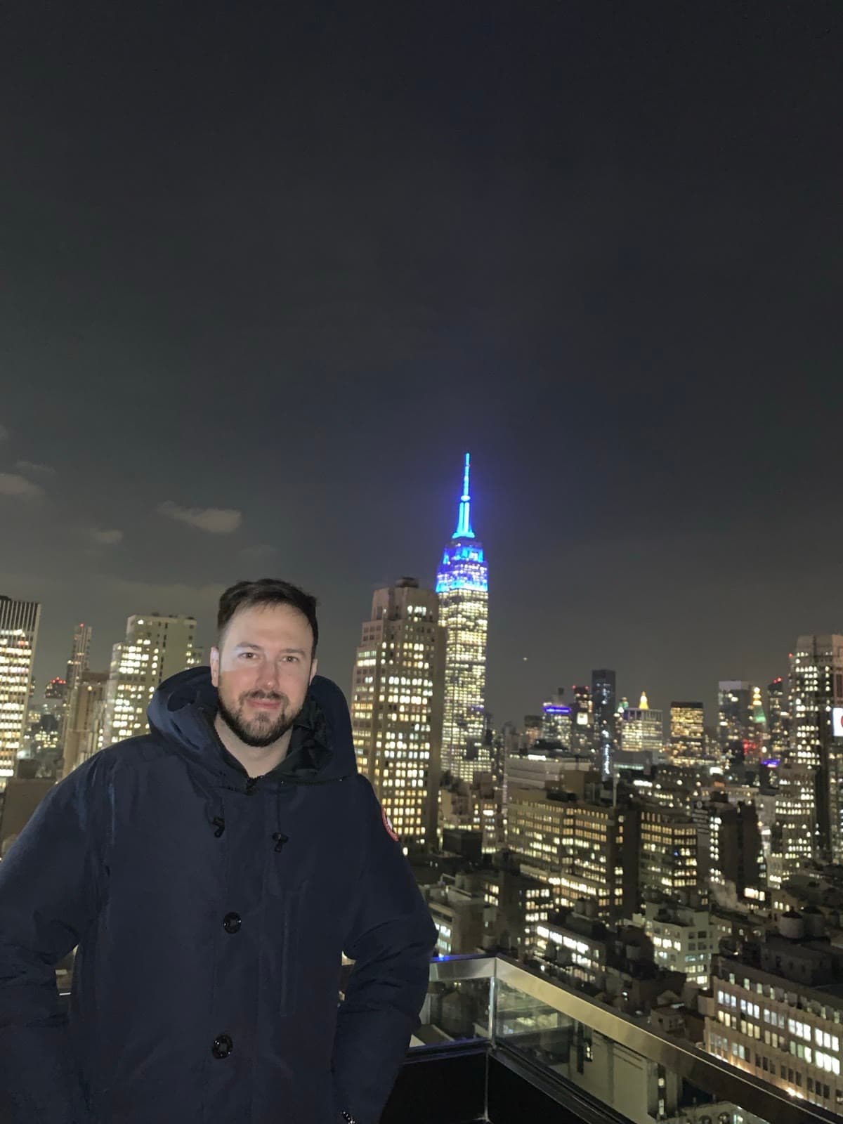 Oliver Locke on a Manhattan rooftop at night with the Empire State Building behind him
